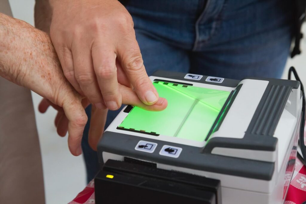Close-up of a Live Scan technician scanning an applicant's fingerprint on a fingerprinting device.