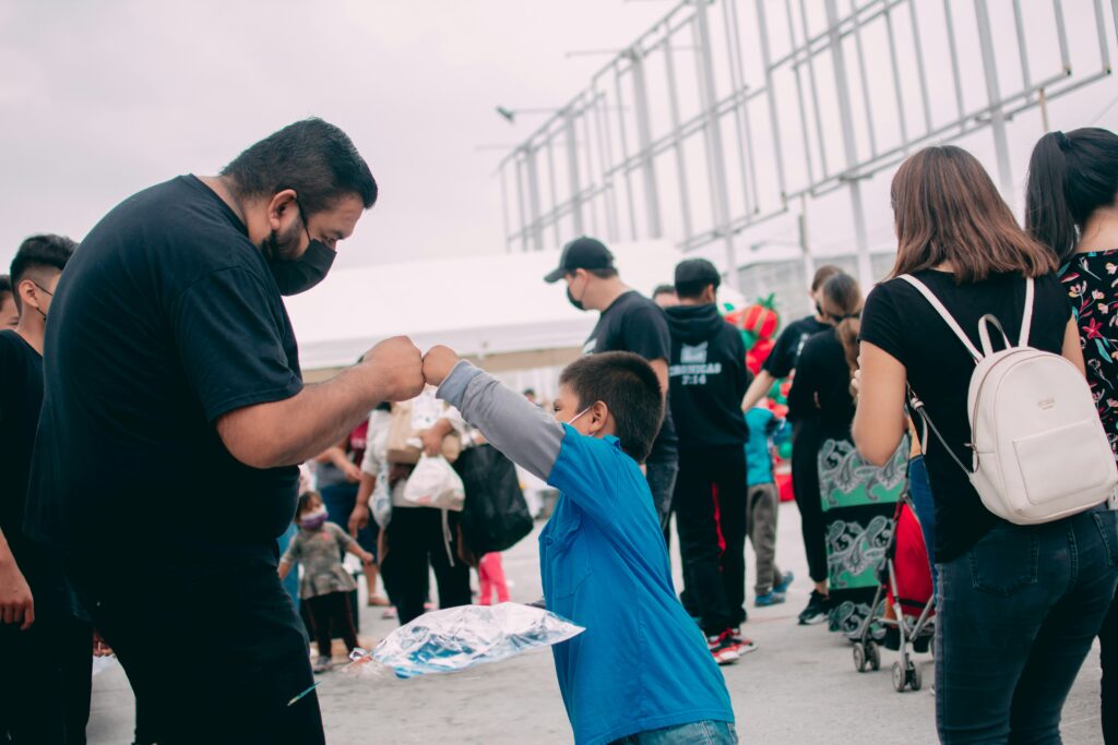 Volunteer fist-bumping a young child at a California community outreach event.