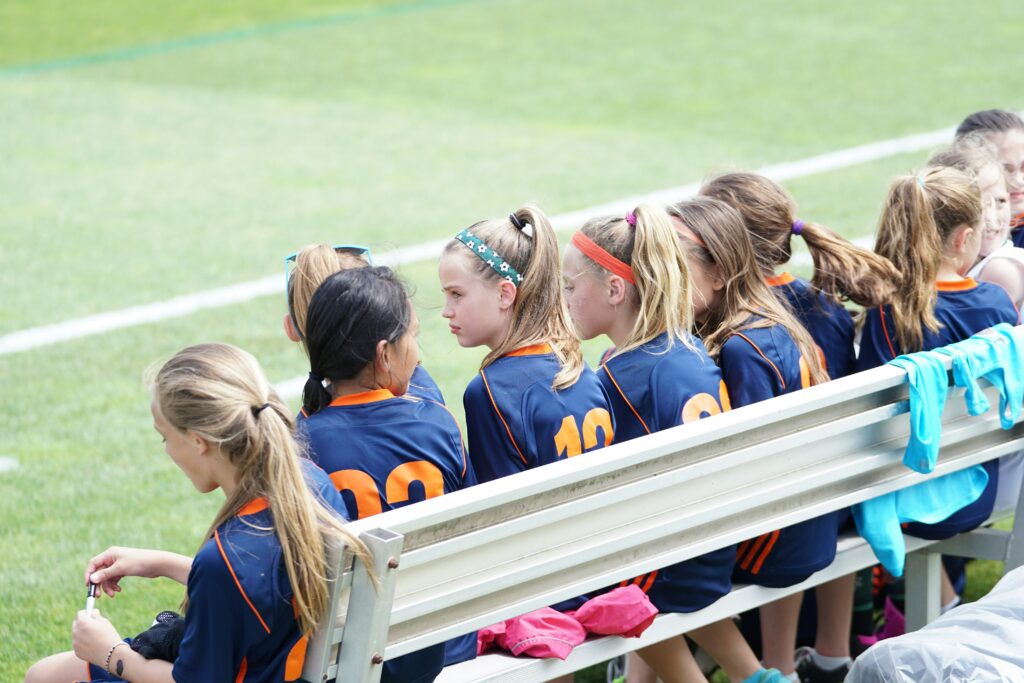Children seated on a bench for a youth soccer game.