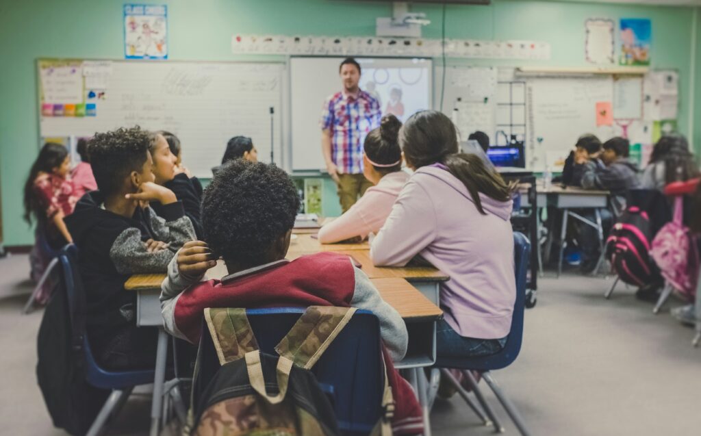 Classroom of students with a teacher at the front teaching.